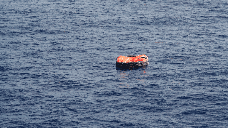 A lone, empty life raft adrift on the water.